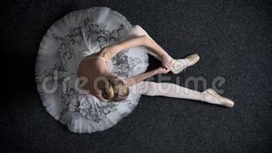 年轻女孩芭蕾舞者的剪影带在尖角上，坐在地板上，芭蕾概念，<strong>顶级</strong>镜头